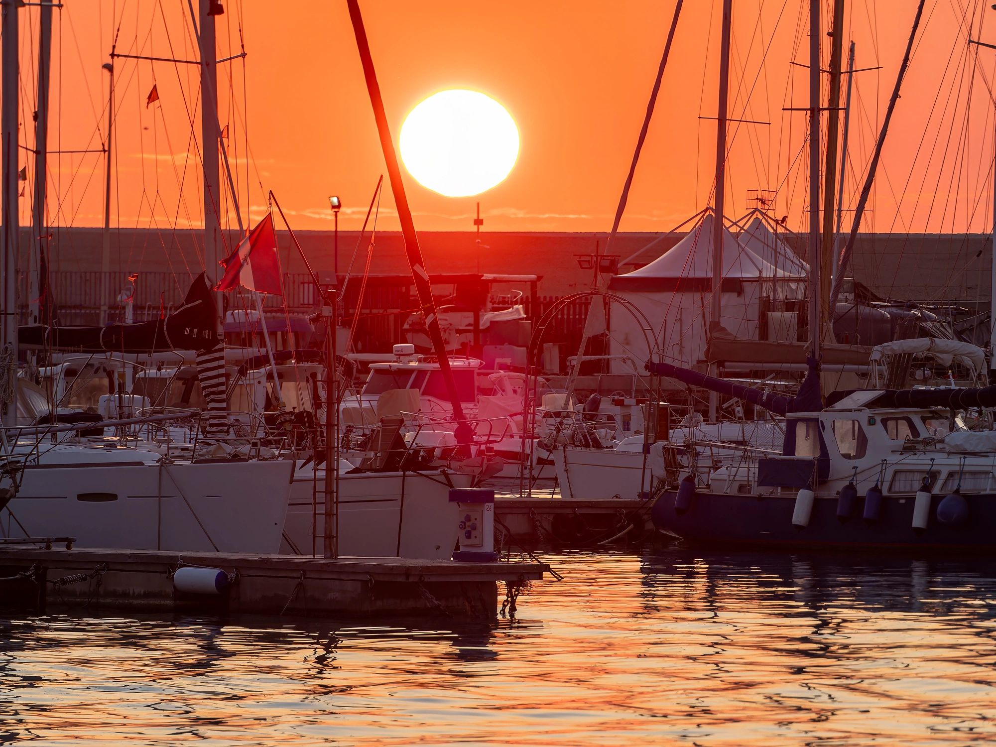 Sailing boats in a marina at sunset